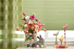 It’s not easy, being green cellular shades with green drapes pulled aside to the left of the window, behind a table decorated for Easter, chocolate bunny, easter eggs