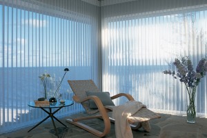 White sheer vertical blinds room looking out at the ocean and blue sky